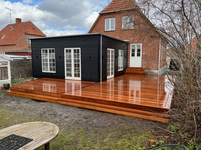 Elegant træterrasse i mørkt træ ved sort og rødt murstenshus i Lyngby