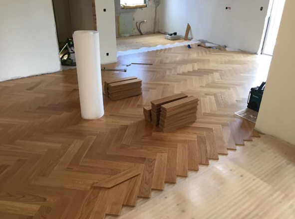 Tømrerarbejde med sildebensparketgulv under installation.